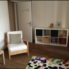 Salle d'attente du cabinet avec une étagère et un tapis au sol